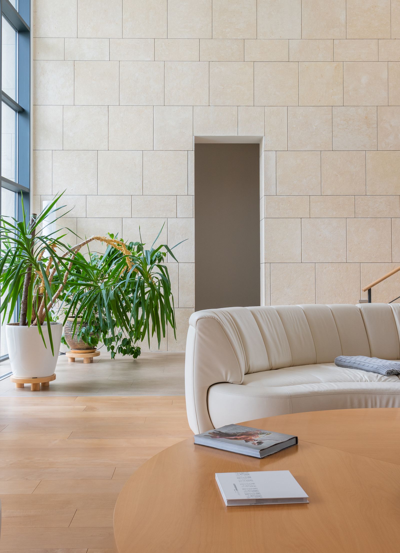 Lichte woonkamer met witte muren, een lichte bank, ronde tafel en veel planten in Scandinavische stijl