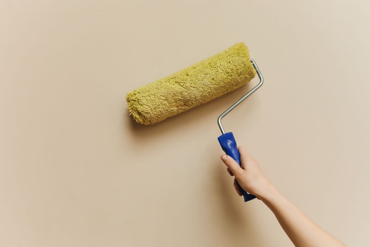 Verfroller op een warm beige geverfde muur