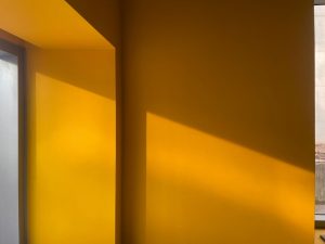 Warm gele muur in een interieur met zonlicht