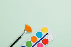 Aquarelpalet en penseel op een zachtgroene achtergrond