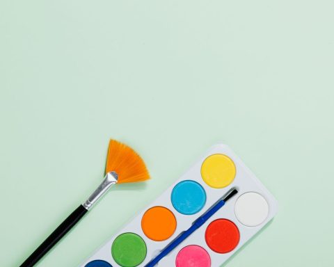 Aquarelpalet en penseel op een zachtgroene achtergrond