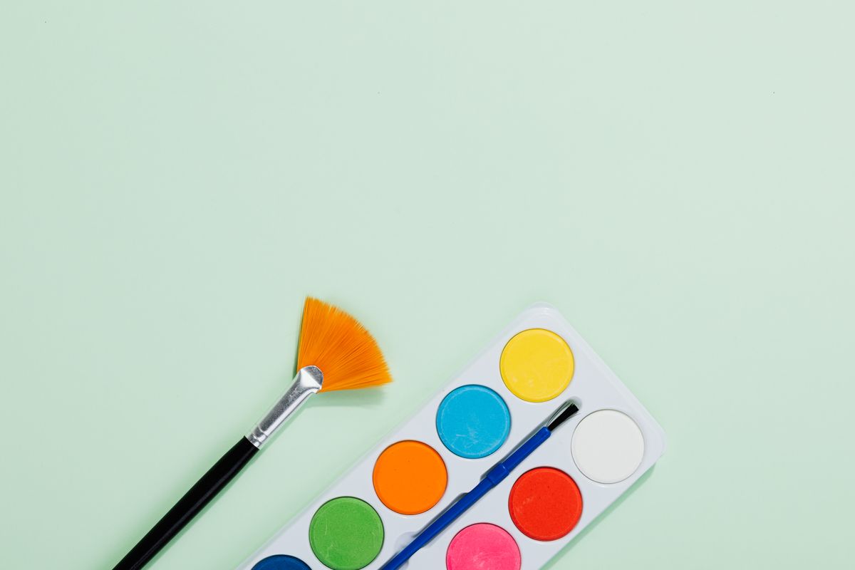 Aquarelpalet en penseel op een zachtgroene achtergrond