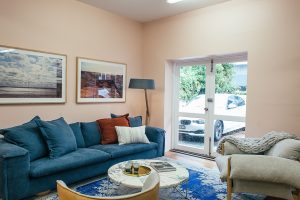 Lichte woonkamer met blauwe bank, fauteuil en ingelijste kunst aan de muur