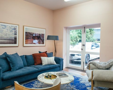 Lichte woonkamer met blauwe bank, fauteuil en ingelijste kunst aan de muur