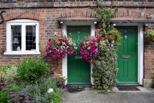 Bakstenen huis met donkergroene voordeuren en bloemen