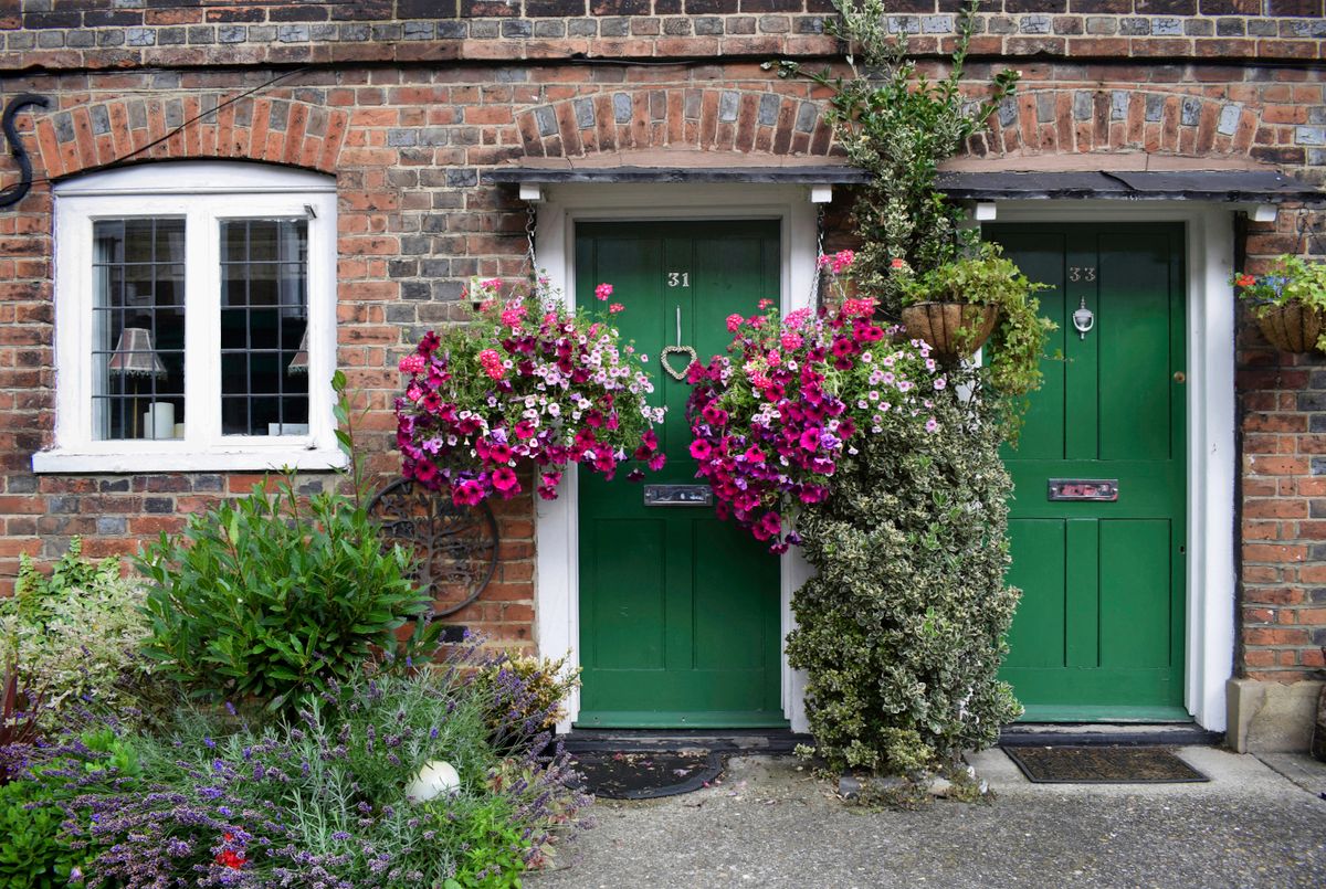 Bakstenen huis met donkergroene voordeuren en bloemen