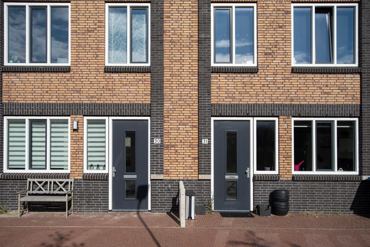 Bakstenen rijtjeshuizen met antracietgrijze voordeuren en witte kozijnen