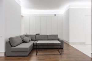 Minimalistische woonkamer met lichtgrijze bank en witte muren