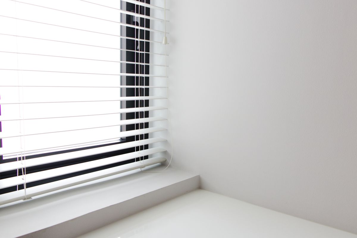 Minimalistisch wit interieur met helderwit raam en lamellen