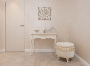 Lichte hal met beige muren, een beige tafel en een zachte poef in een rustig, neutraal interieur