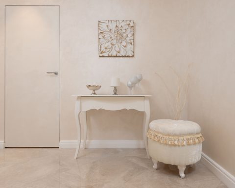 Lichte hal met beige muren, een beige tafel en een zachte poef in een rustig, neutraal interieur